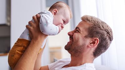 Smilende far løfter og kigger på en baby